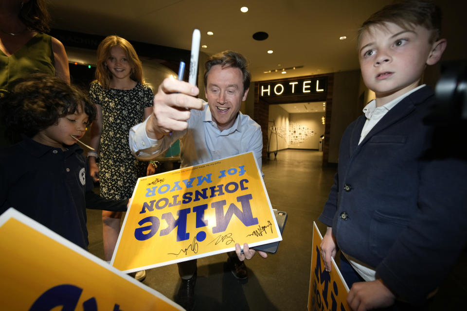 Denver mayoral candidate Mike Johnston autographs yard signs for the children of his supporters before entering an election eve watch party in a hotel late Tuesday, April 4, 2023, in lower downtown Denver. Johnston and Kelly Brough were the top vote-getters in the race, which featured 16 candidates. (AP Photo/David Zalubowski)