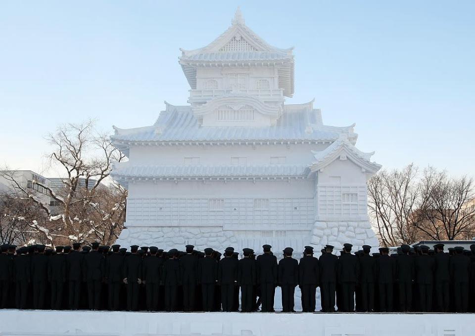 Members of Japan's Self Defence Force stand in front of a snow castle at Odori Park on February 4, 2008 in Sapporo, Japan.