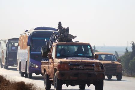 Fighters from a coalition of rebel groups called "Jaish al Fateh", also known as "Army of Fatah" (Conquest Army), escort buses evacuating fighters and civilians from the two besieged Shi'ite towns of al-Foua and Kefraya in the mainly rebel-held northwestern province of Idlib, Syria December 28, 2015. REUTERS/Ammar Abdullah