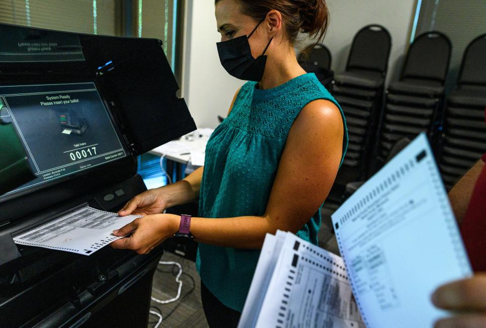 Election judges submit test ballots into a machine during a public accuracy test of voting equipment on August 3, 2022 in Burnsville, Minnesota.