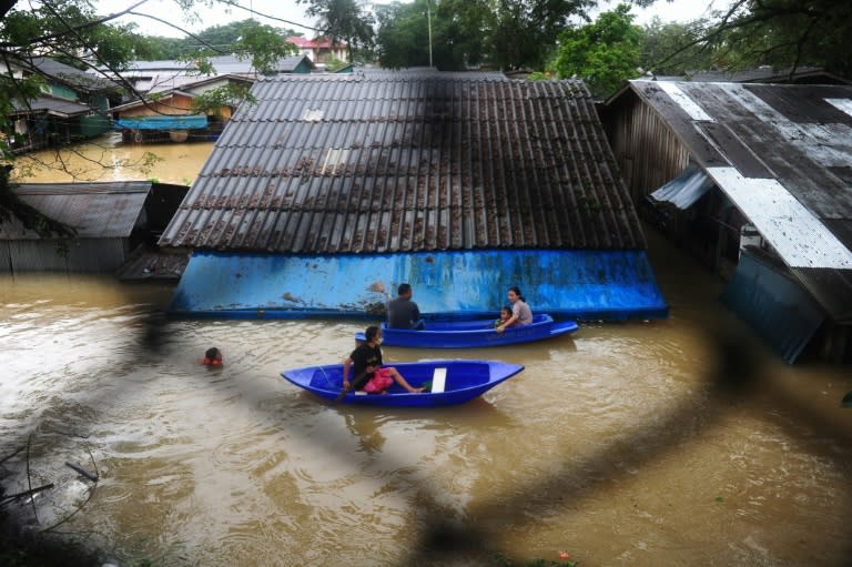 People navigate floodwaters by boat after heavy rains in Sungai Kolok district in the southern Thai province of Narathiwat on January 2, 2017