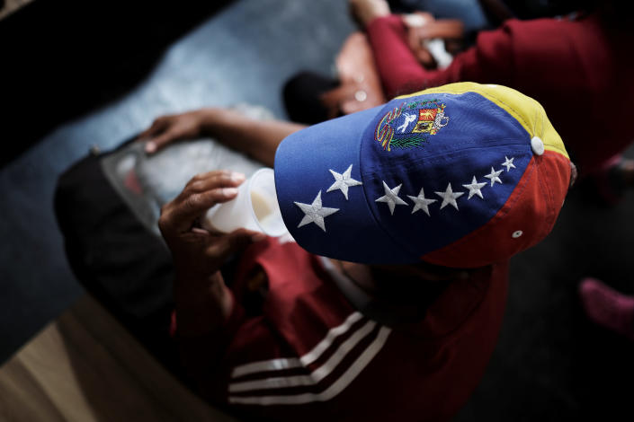 <p>A Venezuelan woman wears a cap with the colors of Venezuelan flag as she drinks coffee with milk after receiving a free vaccination and showing her passport at the Pacaraima border control, Roraima state, Brazil, Aug. 8, 2018. (Photo: Nacho Doce/Reuters) </p>