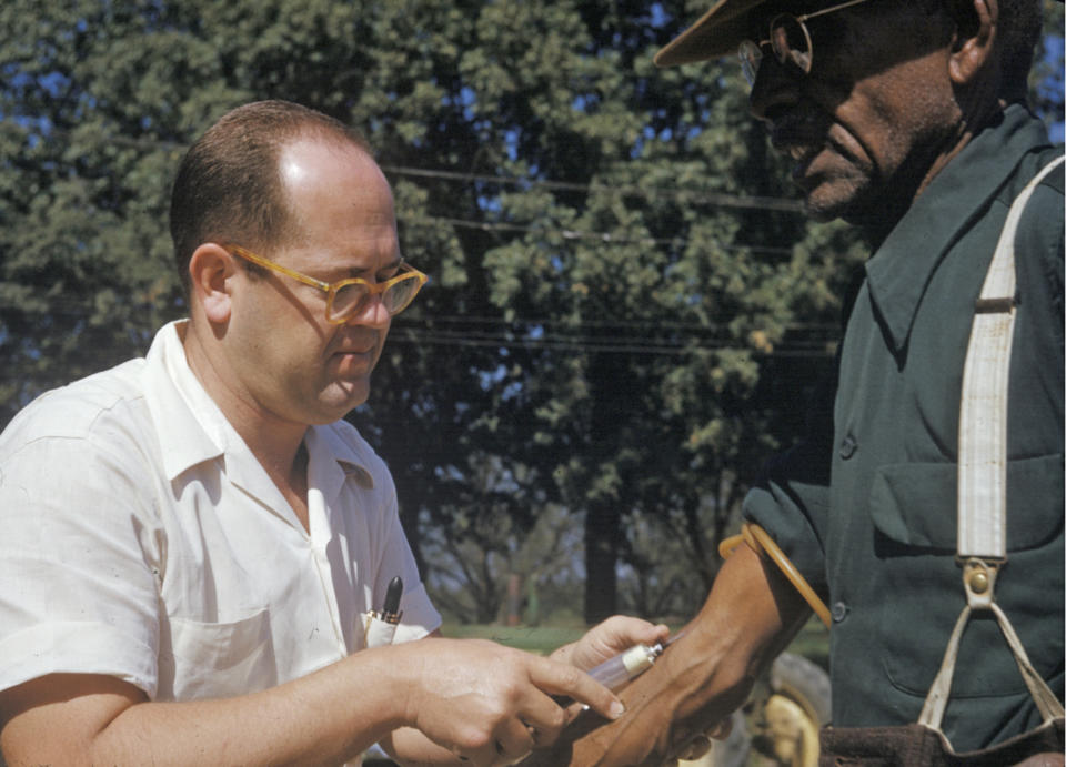 FILE - In this 1950's photo released by the National Archives, a man included in a syphilis study has blood drawn by a doctor in Tuskegee, Ala. For 40 years starting in 1932, medical workers in the segregated South withheld treatment for Black men who were unaware they had syphilis, so doctors could track the ravages of the illness and dissect their bodies afterward. Finally exposed in 1972, the study ended and the men sued, resulting in a $9 million settlement. (National Archives via AP)