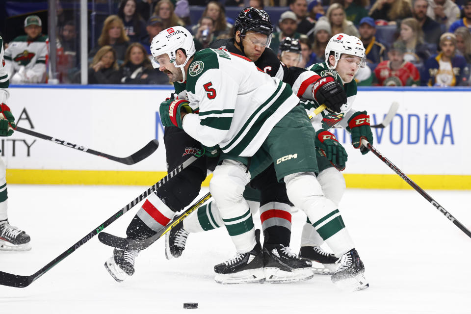 Buffalo Sabres right wing Kyle Okposo (21) is checked by Minnesota Wild defenseman Jake Middleton (5) during the first period of an NHL hockey game, Saturday, Jan. 7, 2023, in Buffalo, N.Y. (AP Photo/Jeffrey T. Barnes)