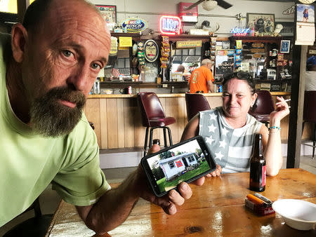 Jerry Strickland, a local resident who believes the county's Confederate monument should stay put shows off a photo of the Confederate flag on the front of his home as girlfriend Tina Hinnicutt looks on in the Court Square Bar in Graham, North Carolina, U.S August 23, 2017. REUTERS/Colleen Jenkins