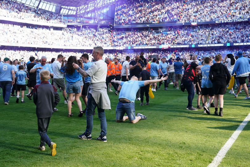 Fans celebrate on the pitch at the Etihad after beating West Ham to seal an unprecedented fourth consecutive Premier League title -Credit:PA