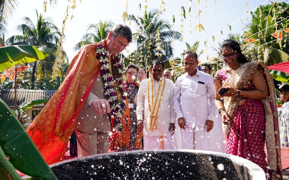 Sir Tim smashes a coconut, a ritual believed to banish bad luck