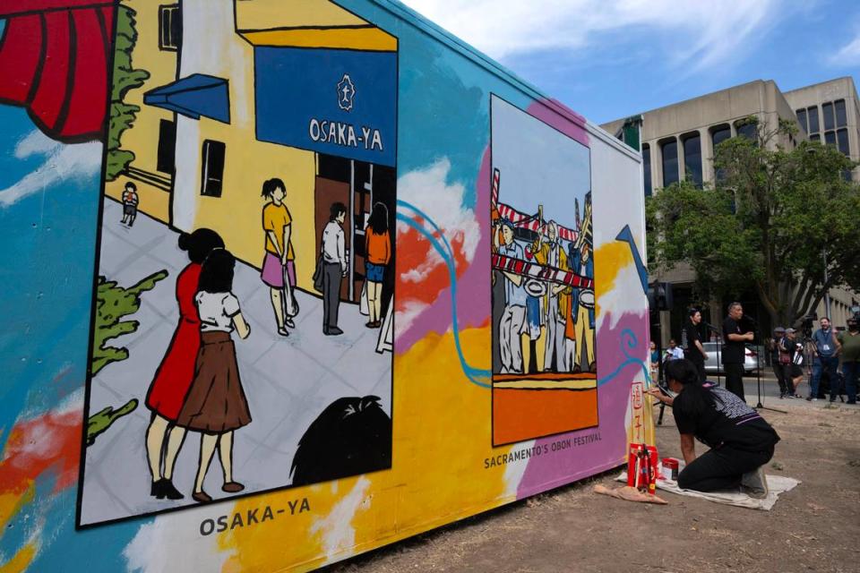 Artist Karen Tsugawa makes a rakkan-in, an artist’s signature, on the Sacramento Japantown mural located at Capitol Mall and 4th Street on Wednesday.