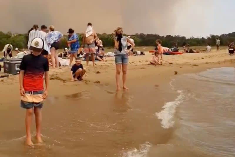 Una multitud de personas en la playa evacuada por los incendios forestales en Batemans Bay, Australia, el 31 de diciembre de 2019, en esta imagen obtenida de un video colgado en redes sociales