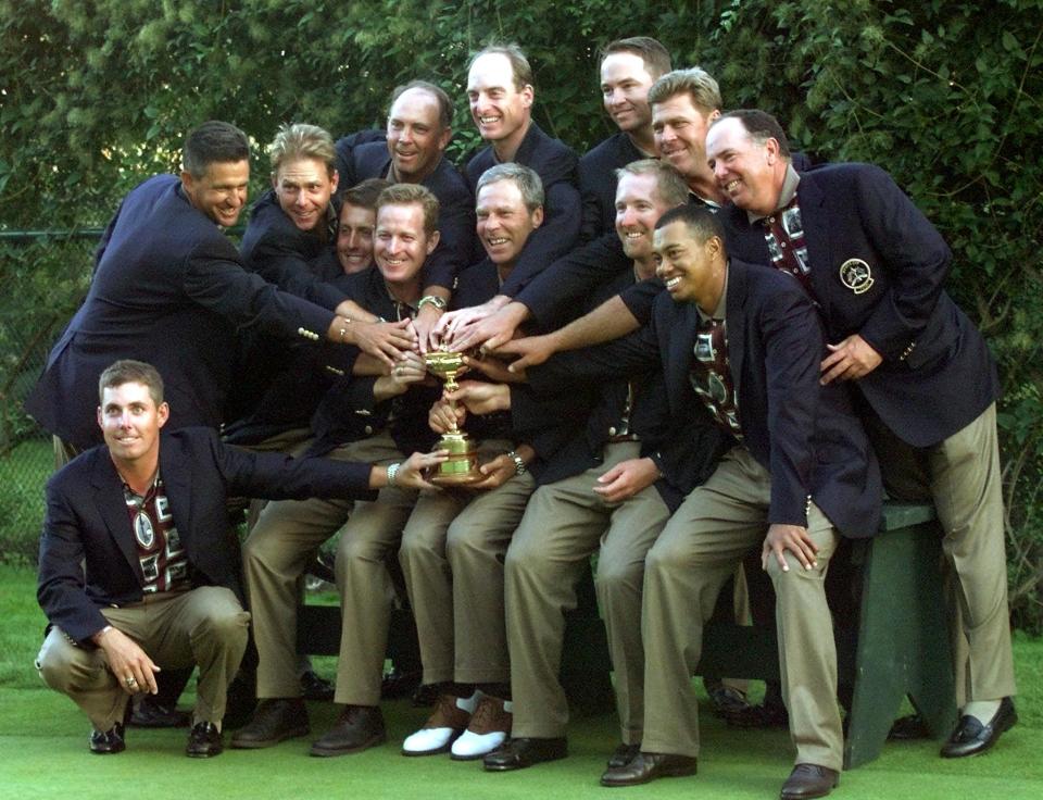 US Ryder Cup team members touch the Ryder Cup during team pictures 26 September,1999 after winning at The Country Club in Brookline, Massachusetts. The US defeated the European team 14 1/2 to 13 1/2. (Photo by Timothy A. CLARY / AFP)