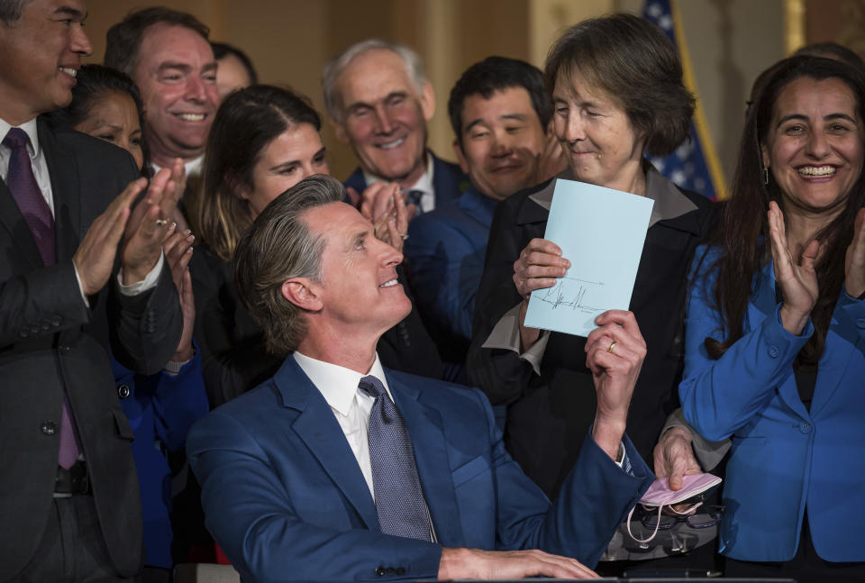 Gov. Gavin Newsom hands a signed bill to Sen. Nancy Skinner, D-Berkeley, who was the author of the bill, in the Capitol rotunda in Sacramento, Calif., Tuesday, March 28, 2023. (Xavier Mascareñas/The Sacramento Bee via AP)