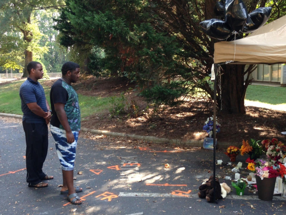 <p>Abdelrazig Abdelrazig, left, 21, and his brother Ibraheem Abdelrazig, 19, visit a memorial to Keith Scott in a townhouse parking lot, Sunday, Sept. 25, 2016, near where he was killed in Charlotte, N.C. (AP Photo/Emery P. Dalesio)</p>