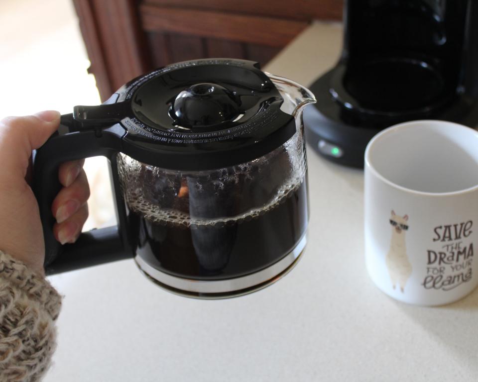 Contributing editor, Camryn Rabideau using Mr. Coffee 5-cup drip filter coffee maker to make black coffee. She is pouring into a novelty mug