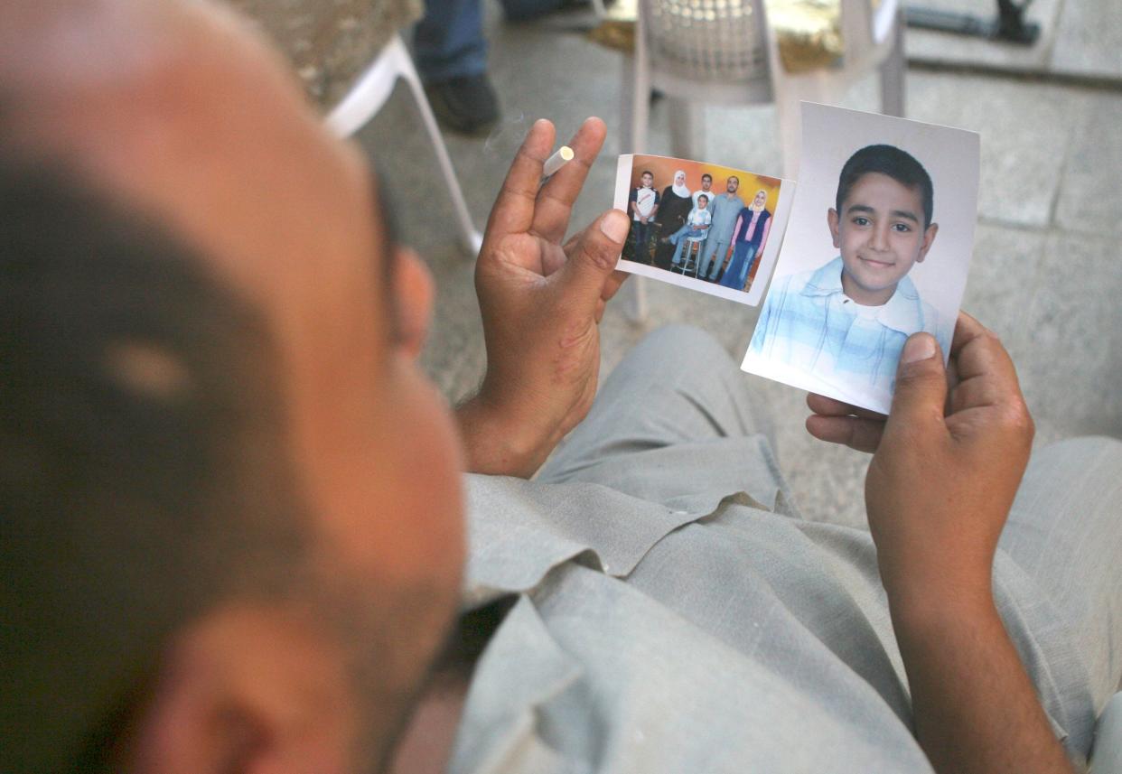 Mohammed Hafiz looks at photos of his 10-year-old son in Baghdad on Oct. 4, 2007. The boy died after the attack on Iraqi civilians by U.S. Blackwater contractors on Sept. 16, 2007. (Photo: AP Photo/Khalid Mohammed)