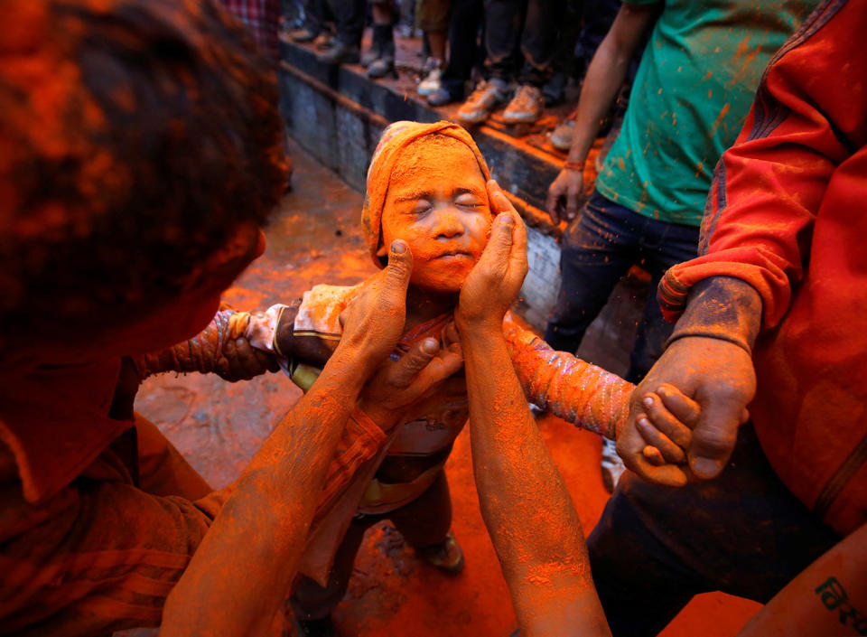 A boy gets his face smeared with vermillion powder in Bhaktapur