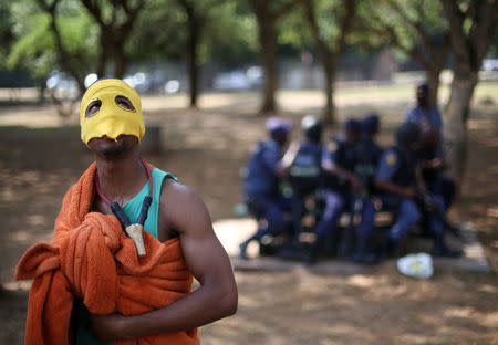 A protester wearing a mask gestures infront of riot police officers during a march to South African President Jacob Zuma's offices, to demand free university education, in Pretoria, South Africa,October 20, 2016. REUTERS/Siphiwe Sibeko