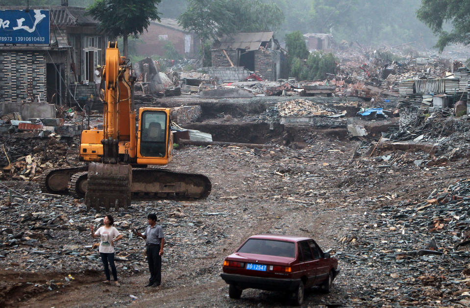 In this photo taken on Wednesday, July 25, 2012, People look at the houses damaged by floods in Fangshan district in Beijing, China. Chinese authorities on Thursday raised Beijing storm's death toll to 77 after the public questioned the days-old tally of 37, with some residents even compiling their own totals in a reflection of deep mistrust of the government's handling of the disaster. (AP Photo) CHINA OUT