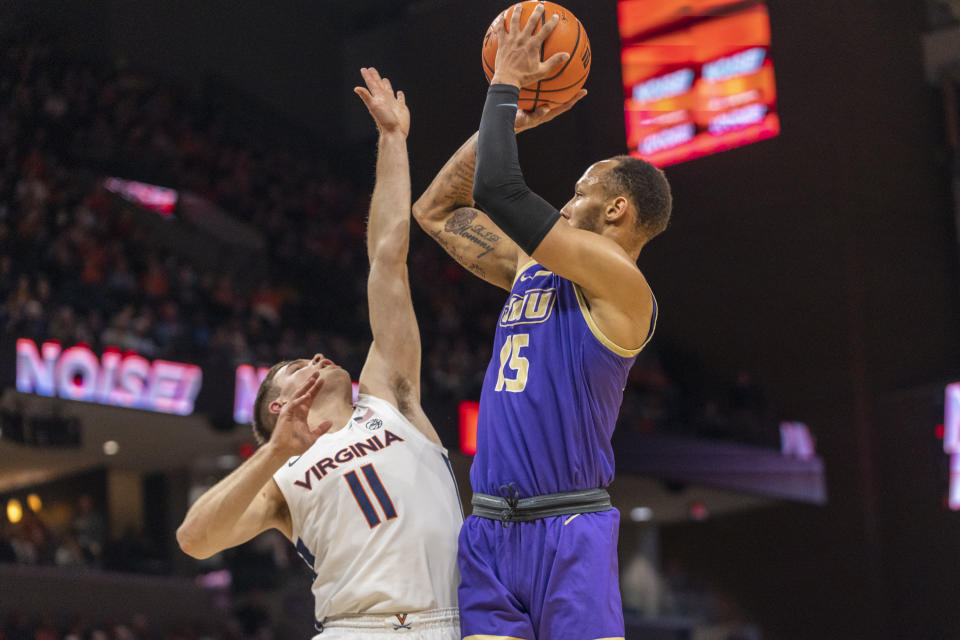 James Madison guard Takal Molson (15) shoots over Virginia's Isaac McNeely during the first half of an NCAA college basketball game in Charlottesville, Va., Tuesday, Dec. 6, 2022. (AP Photo/Erin Edgerton)