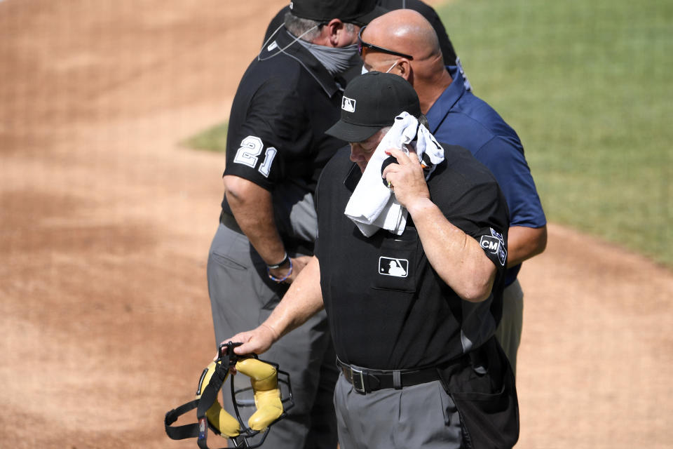 Home plate umpire Joe West, foregroundr, is led off the field after he was injured during the first inning of a baseball game between the Toronto Blue Jays and the Washington Nationals, Thursday, July 30, 2020, in Washington. (AP Photo/Nick Wass)