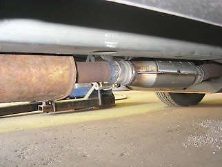 A muffler, on the left, and a catalytic converter, on the right, are seen on a newly repaired Jeep at Tom Cherry Muffler.