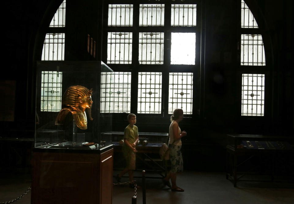 In this Wednesday, Oct. 30, 2013 photo, the solid gold mask of King Tutankhamun is seen in its glass case, as tourists visit the Egyptian museum near Tahrir Square in Cairo, Egypt. The 111-year-old museum, a treasure trove of pharaonic antiquities, has long been one of the centerpieces of tourism to Egypt. But the constant instability since the 2011 uprising that toppled autocrat Hosni Mubarak has dried up tourism to the country, slashing a key source of revenue. Moreover, political backbiting and attempts to stop corruption have had a knock-on effect of bringing a de facto ban on sending antiquities on tours to museums abroad, cutting off what was once a major source of funding for the museum. (AP Photo/Nariman El-Mofty)