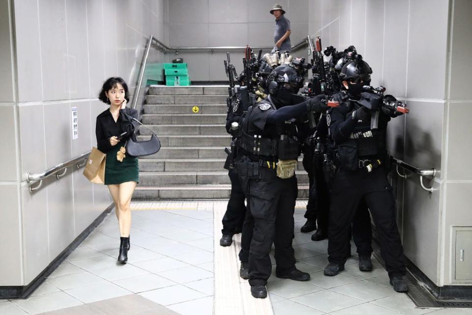 A woman walks past as South Korean soldiers participate in an anti-chemical and anti-terror exercise