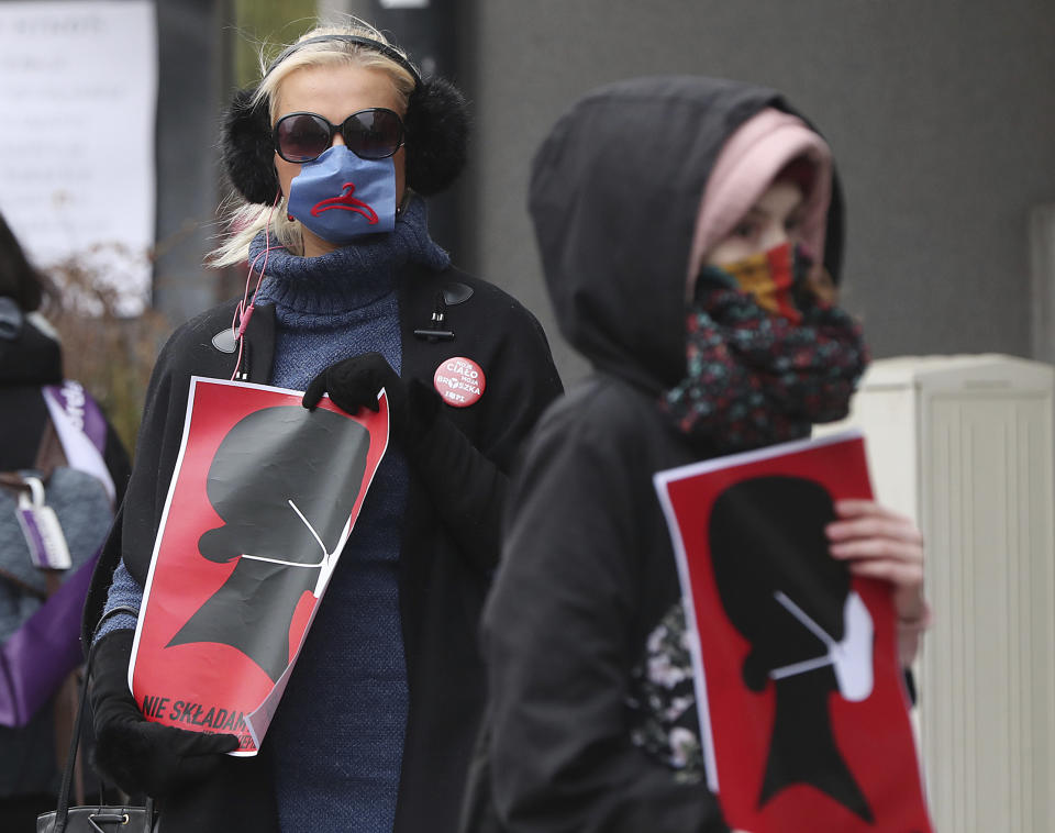 Women's rights activists, wearing masks against the spread of the coronavirus, protest against a draft law tightening Poland's strict anti-abortion law near the parliament that was debating the draft law, in Warsaw, Poland, on Wednesday, April 15, 2020. (AP Photo/Czarek Sokolowski)