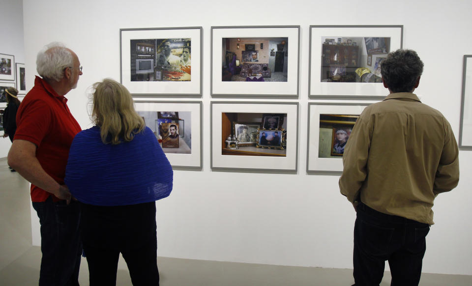 Visitors view photos by Palestinian photographer Ahlam Shibli, at the Jeu de Paume museum in Paris, Wednesday June 12, 2013. The exhibit which started last week at the Jeu de Paume, features dozens of photographs with captions that glorify dead members of Palestinian groups. (AP Photo/Remy de la Mauviniere)