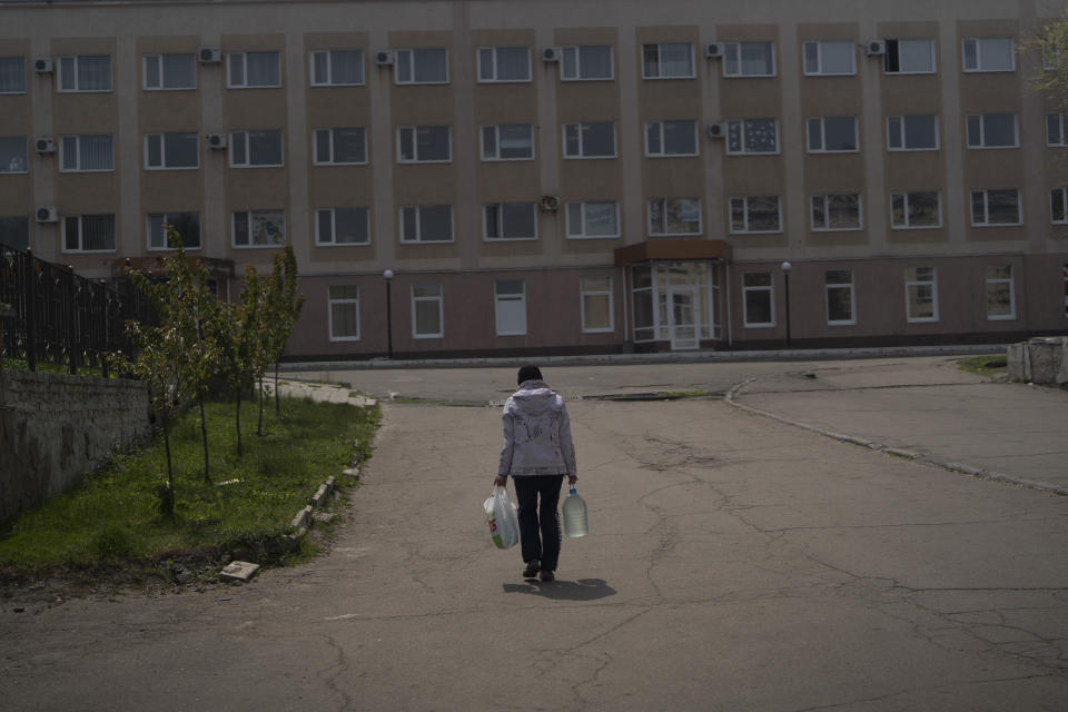 An elderly woman carries a can with water after collecting it from a firefighters truck in Lysychansk, Luhansk region, Ukraine, Friday, May 13, 2022. (AP Photo/Leo Correa)