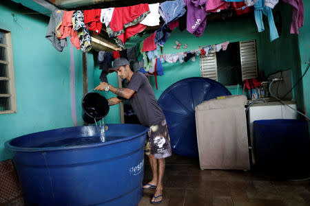 Roberto Souza uses a bucket to collect water in an improvised reservoir, on the day of water rationing, in his neighborhood in Brasilia, Brazil March 21, 2018. REUTERS/Ueslei Marcelino