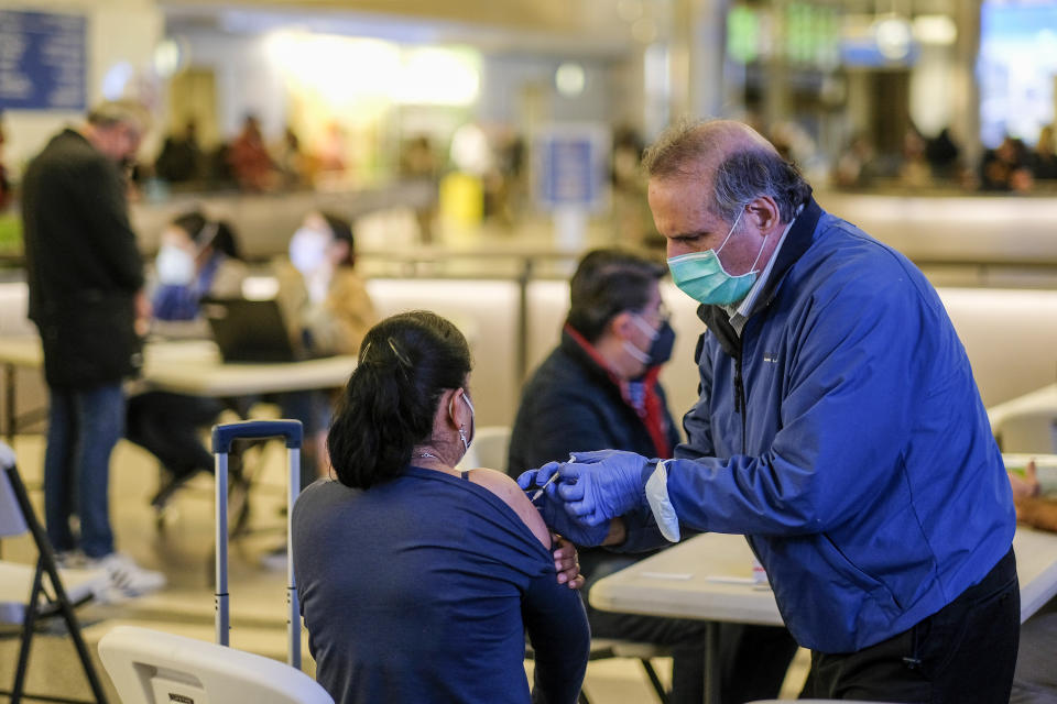 A traveler is vaccinated at the Los Angeles International Airport in Los Angeles, Wednesday Dec. 22, 2021. People traveling during the holiday season can get free COVID-19 vaccinations and booster shots at LAX on two consecutive Wednesdays -- today and Dec. 29. The pop-up clinic, located at the Lower/Arrivals Level of the Tom Bradley International Terminal, will be open from 11 a.m. to 5 p.m. on the two days. (AP Photo/Ringo H.W. Chiu)