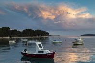 Because of lack of tourists, the beach is empty and only few boats are moored in the harbor in Fazana, Croatia, Tuesday, May 26, 2020. "Our Dream Their Smile" group has helped people in the tourism-dependent area in the Adriatic survive as the outbreak closed down borders, shutting down hotels, restaurants and other businesses that normally thrive in virus-free times. (AP Photo/Darko Bandic)