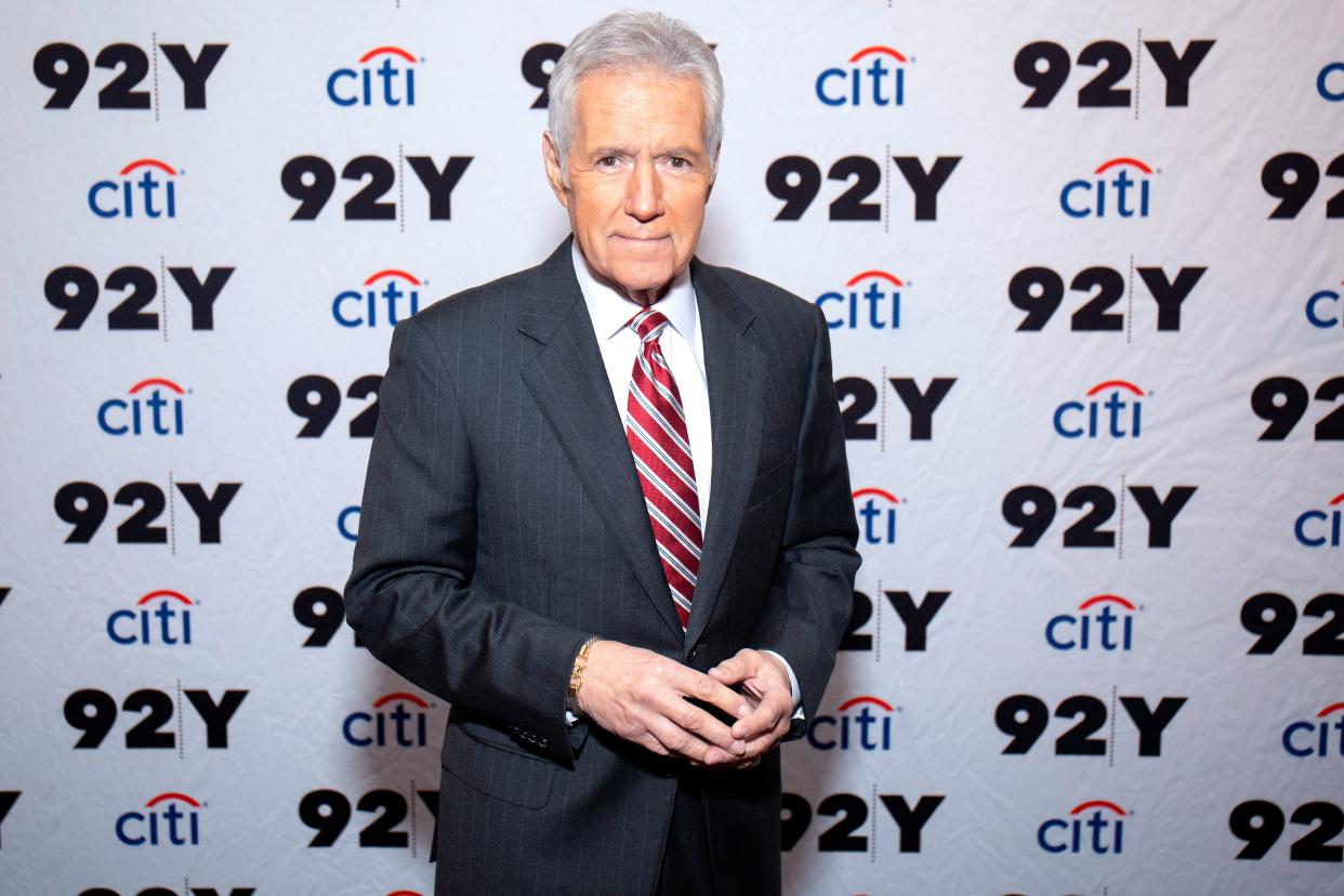 Alex Trebek poses wearing a red and white striped tie