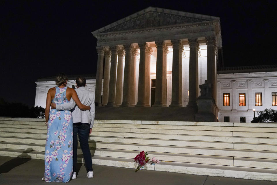 A couple pauses outside the Supreme Court Friday, Sept. 18, 2020, in Washington, after the Supreme Court announced that Supreme Court Justice Ruth Bader Ginsburg has died of metastatic pancreatic cancer at age 87. (AP Photo/Alex Brandon)