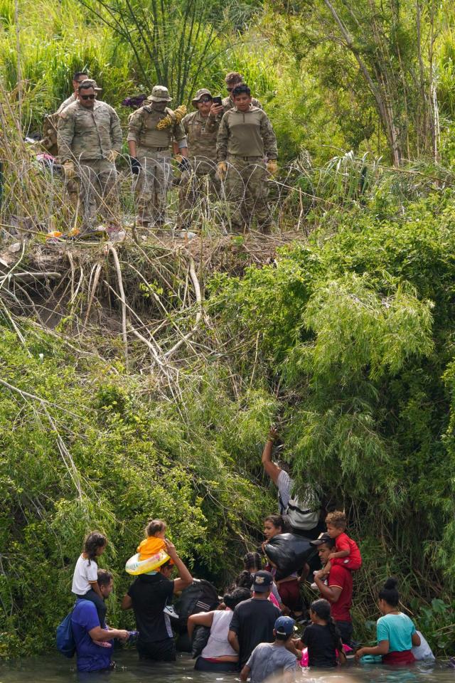 Migrants climb the bank of the Rio Grande as Texas state police finish placing barbed-wire, seen from Matamoros, Mexico, Wednesday, May 10, 2023. The U.S. on May 11 will begin denying asylum to migrants who show up at the U.S.-Mexico border without first applying online or seeking protection in a country they passed through. (AP Photo/Fernando Llano)