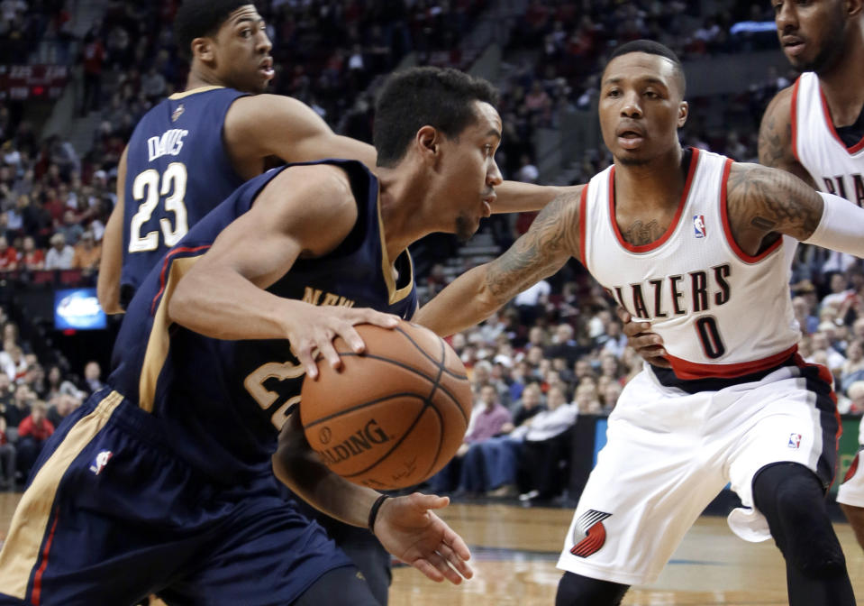 New Orleans Pelicans guard Brian Roberts, left, drives on Portland Trail Blazers guard Damian Lillard during the first half of an NBA basketball game in Portland, Ore., Sunday, April 6, 2014. (AP Photo/Don Ryan)