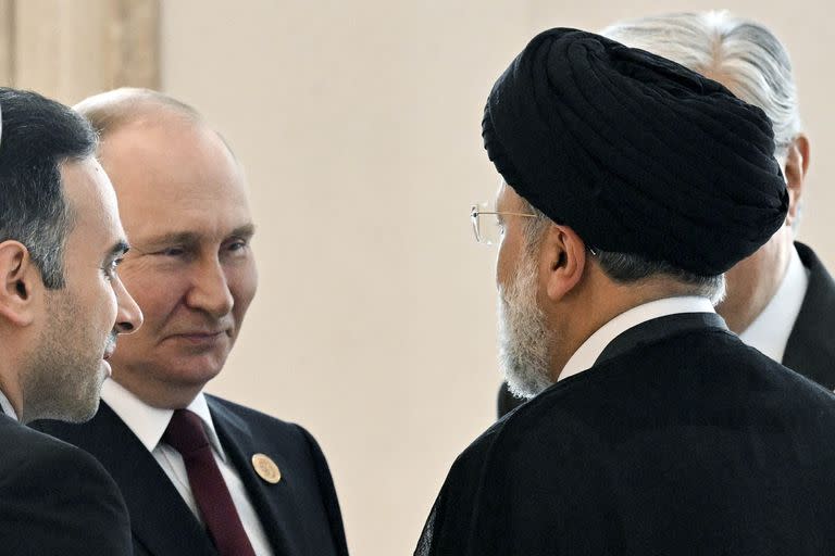 El presidente ruso Vladimir Putin, a la izquierda, habla con el presidente de Irán, Ebrahim Raisi, de espaldas a una cámara, al margen de la cumbre de los estados litorales del Mar Caspio en Ashgabat, Turkmenistán, el miércoles 29 de junio de 2022. 