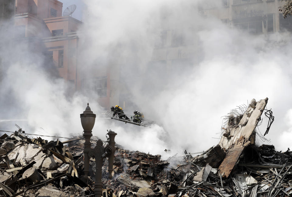 Firefighters used ladders climb over the charred rubble of the destroyed building. Source: AP