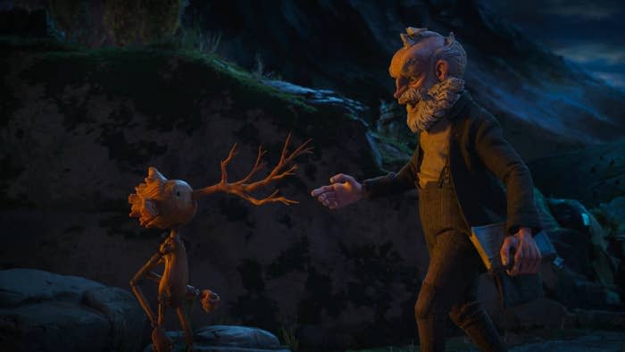 A wooden puppet boy’s nose branches into a tree while an old man looks at him