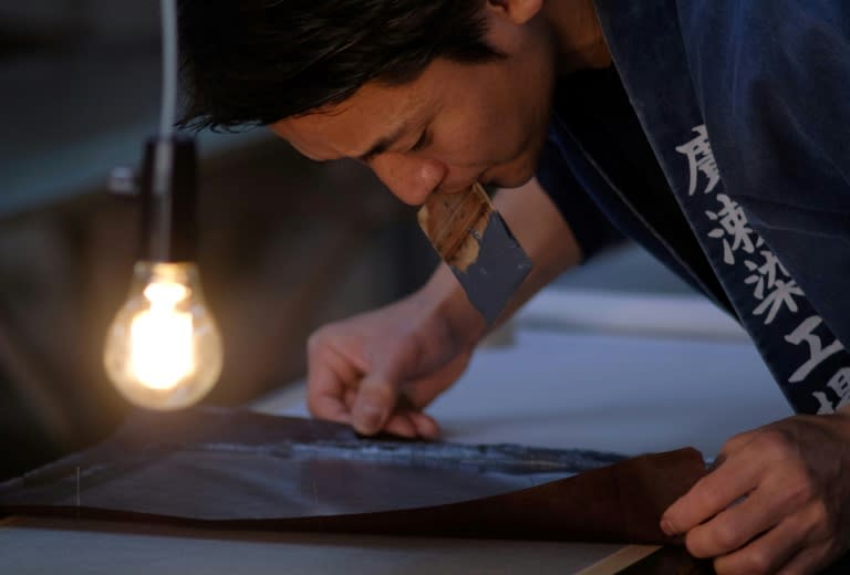 Yuichi Hirose holds a hand-cut stencil to dye a kimono at a century-old workshop in Tokyo