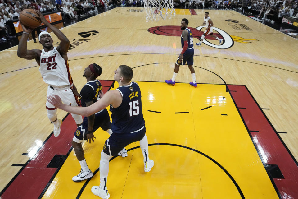 Miami Heat forward Jimmy Butler (22) goes up for a shot against Denver Nuggets guard Kentavious Caldwell-Pope second from left, and center Nikola Jokic (15) during the first half in Game 4 of the basketball NBA Finals, Friday, June 9, 2023, in Miami. (AP Photo/Wilfredo Lee)