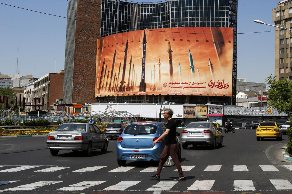 ftse A man crosses a street as motorists drive past a billboard depicting Iranian ballistic missiles in service in Tehran on April 19, 2024. Iran's state media reported explosions in the central province of Isfahan on April 19, as US media quoted officials saying Israel had carried out retaliatory strikes on its arch-rival. (Photo by AFP) (Photo by -/AFP via Getty Images)