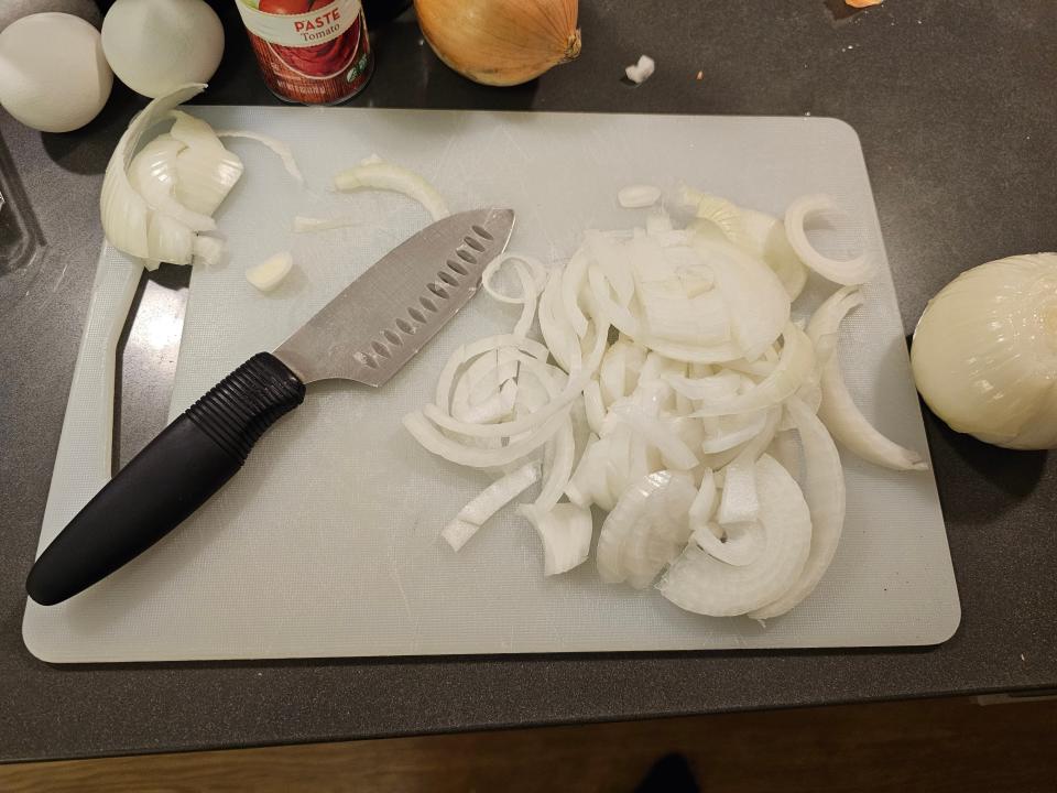 Knife on cutting board next to sliced onions