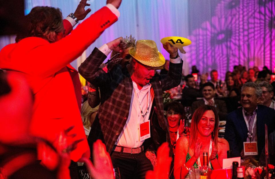 Josh and Lisa Dorcey, center, celebrate a winning bid during the SWFL Wine & Food Fest at Suncoast Credit Union Arena in Fort Myers on Saturday, Jan. 20, 2024. The auction raised over $2 million.