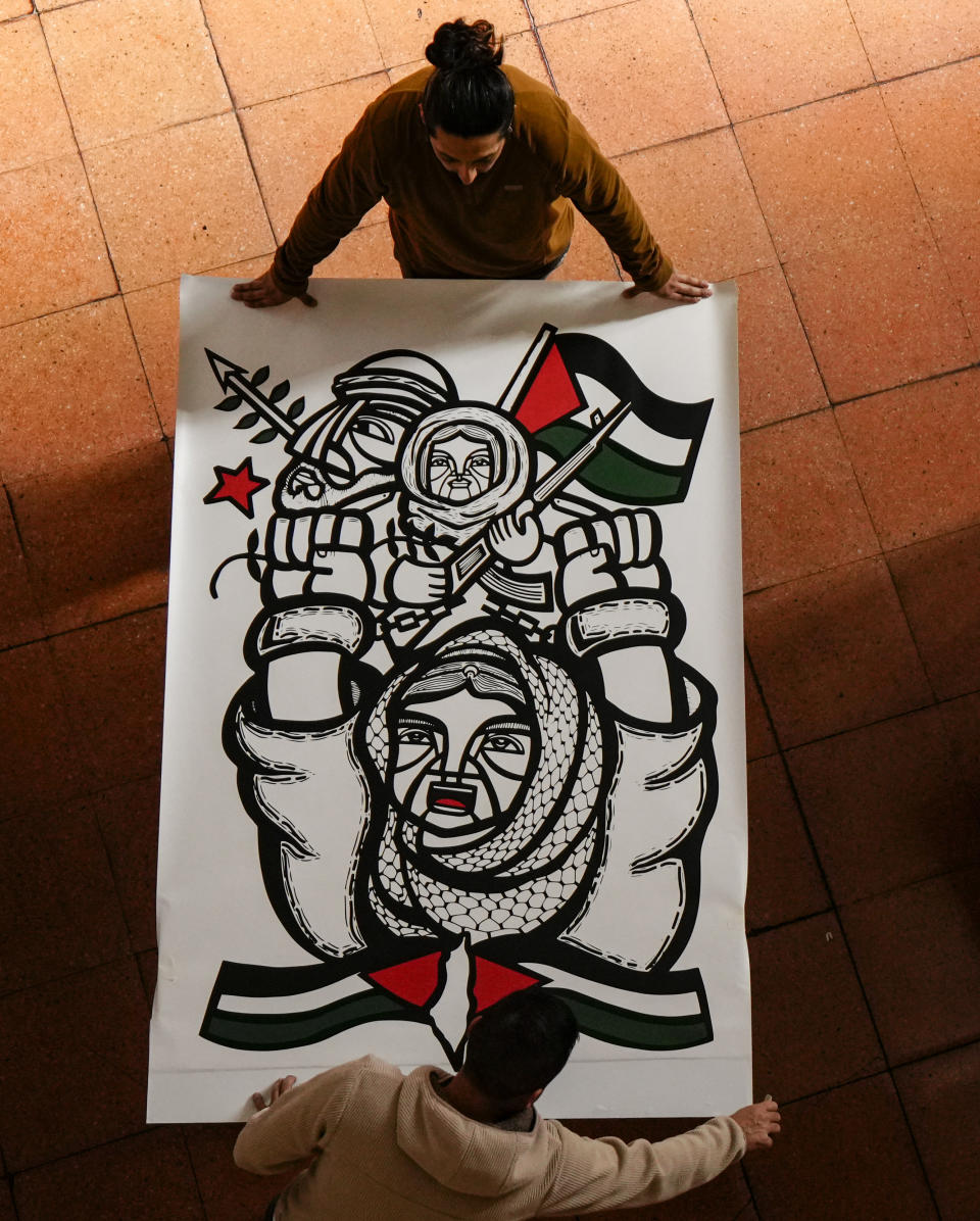 Varios trabajadores preparan obras para una exposición llamada “Desde todos los ríos hasta todos los mares. Gráfica en Solidaridad con Palestina” en el Archivo Nacional de Chile en Santiago, Chile, el miércoles 19 de junio de 2024. (AP Foto/Esteban Félix)