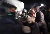 Ukrainian riot police detain a protester, who planned to stop buses carrying passengers evacuated from the Chinese city of Wuhan, outside Novi Sarzhany, Ukraine, Thursday, Feb. 20, 2020. Several hundred residents in Ukraine's Poltava region protested to stop officials from quarantining the evacuees in their village because they feared becoming infected. Demonstrators put up road blocks and burned tires, while Ukrainian media reported that there were clashes with police, and more than 10 people were detained. (AP Photo/Efrem Lukatsky)