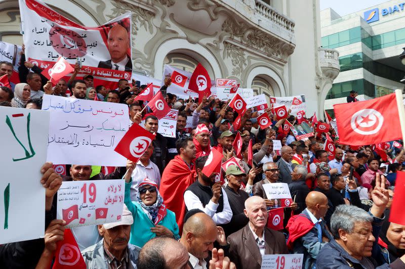 Supporters of Tunisian President Kais Saied carry flags and signs during a demonstration in Tunis