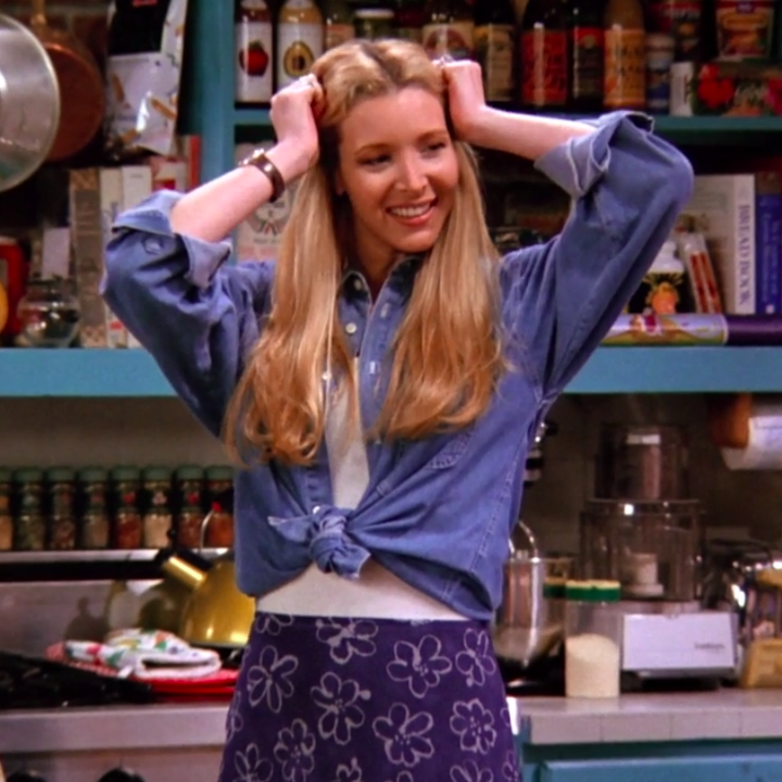 Phoebe wearing heeled boots, a maxi skirt, an undershirt, and a tied button up