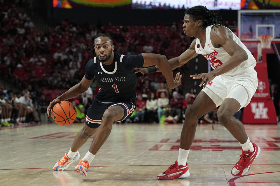 Jackson State forward Zeke Cook (1) drives past Houston forward Joseph Tugler (25) on his way to score during the first half of an NCAA college basketball game, Saturday, Dec. 9, 2023, in Houston. (AP Photo/Kevin M. Cox)