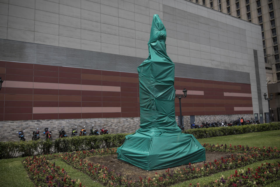 The monument of Inca Garcilaso de la Vega, a mestizo chronicler of the 16th century, is wrapped in a green fabric, in Lima, Peru, Tuesday, Dec. 1, 2020. The municipality of Lima for the the first time in 485 years took precautions to protect historical monuments and statues, while Peru was mired in a whirlwind of demonstrations and a political crisis that resulted with three presidents in nine days. (AP Photo/Rodrigo Abd)